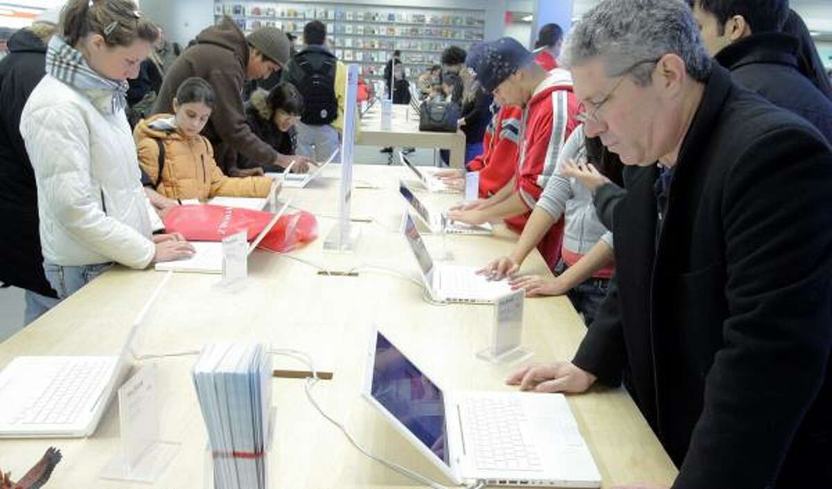 Customers look over Apple computers at a store in New York on Christmas Eve. A report that federal prosecutors are investigating whether former Apple officials forged documents to maximize profit from stock options did not ultimately have a negative effect on the stock price of the maker of iPods.