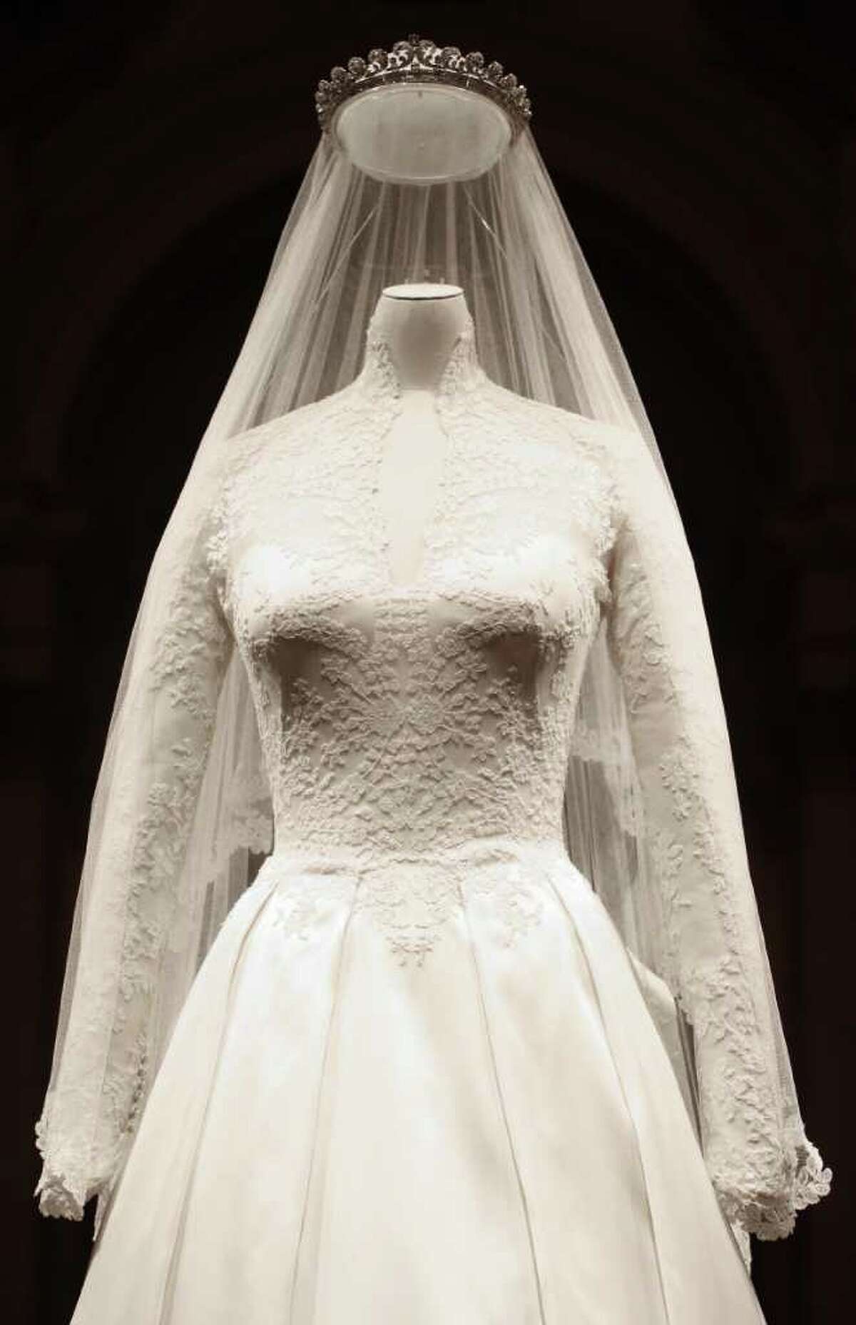 The Duchess of Cambridge's wedding dress, designed by Sarah Burton for Alexander McQueen, is seen in Buckingham Palace, London, Wednesday July 20, 2011, before going on display to the public during the palace's annual summer opening. The intricately decorated wedding dress received a rapturous reception. For months, it was fashion's best-kept secret. Even the team of embroiderers at Hampton Court Palace working on the gown did not know the identity of the designer until shortly before the public announcement. But as soon as the Duchess appeared leaving the Goring Hotel and then entering Westminster Abbey on her wedding day on April 29, the secret was out. The bridal gown featured lace appliqua floral detail and was made of ivory and white satin gazar, with a skirt that resembled "an opening flower" with white satin gazar arches and pleats. Its train measured just 9ft - modest in comparison with many previous royal brides.