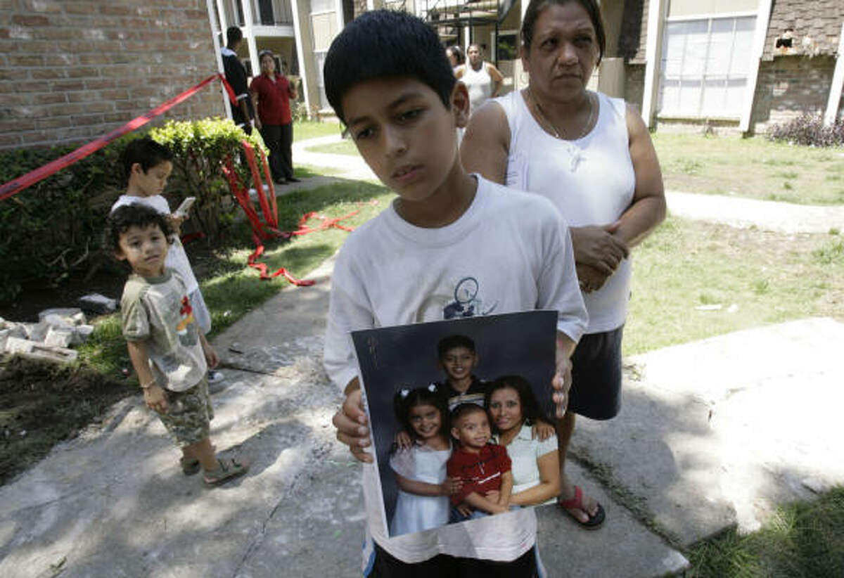 Alexis Robledo holds a family photo showing him on top with his sister Marisol Robledo, left, his brother Miguel Angel Robledo, center, and his mother Miguelina Robledo while standing halfway between his apartment and rubble at a collapsed staircase at the Westwood Fountains Apartments on Thursday.