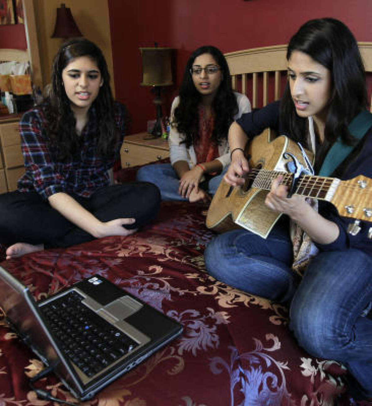 Asma Mirza plays guitar and sings with her sisters Ayesha, 16, left, and Hira, 18, at her Houston-area home. Born in Pakistan, Mirza has lived in the United States for 19 of her 20 years and is a naturalized American citizen.