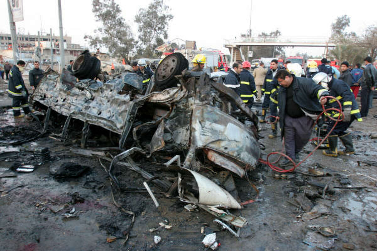 Firefighters work through the wreckage of a vehicle outside al-Mustansiriya University in Baghdad on Tuesday. Two minivans exploded near the university, killing at least 70, as students were leaving classes in the mostly Shiite section of the city.