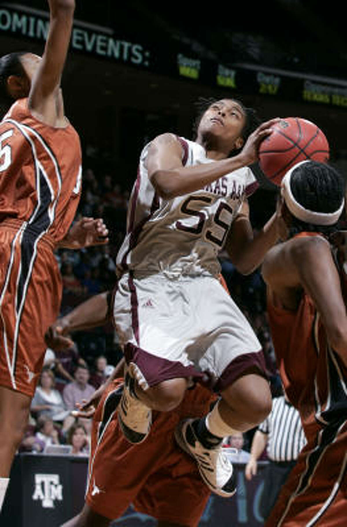 Texas A&M guard Danielle Gant cuts through the Texas defenders Ashley Lindsey, left, and Earnesia Williams during the first half to score two of her 25 points on Feb. 9 at Reed Arena in College Station. A&M defeated Texas 66-57.