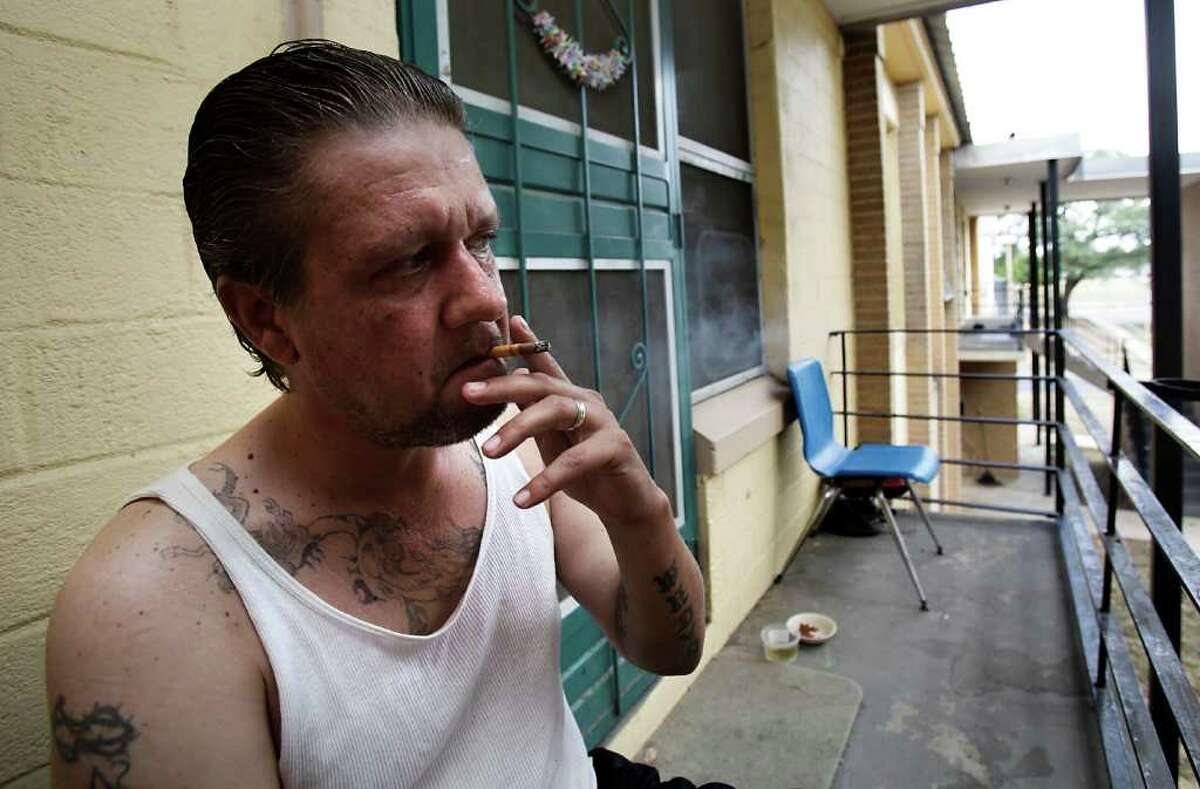 Chris Tatum smokes on the front porch of his Wheatley Courts apartment. Tatum said he tries to avoid smoking inside the apartment, around his stepchildren. Under the prohibition, he wouldn’t even be allowed to smoke there.