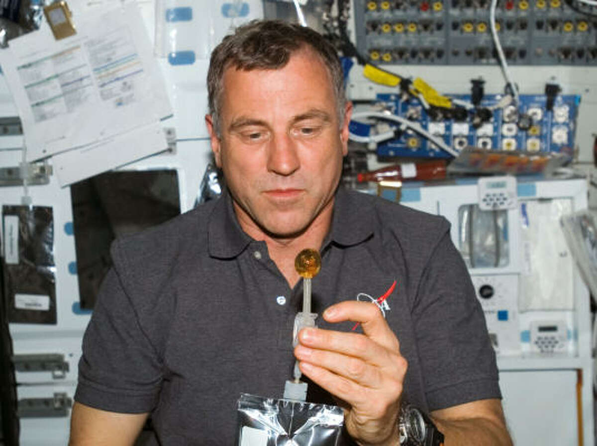 Canadian astronaut Dave Williams squeezes a bubble out of his beverage container Tuesday aboard the space shuttle Endeavour.