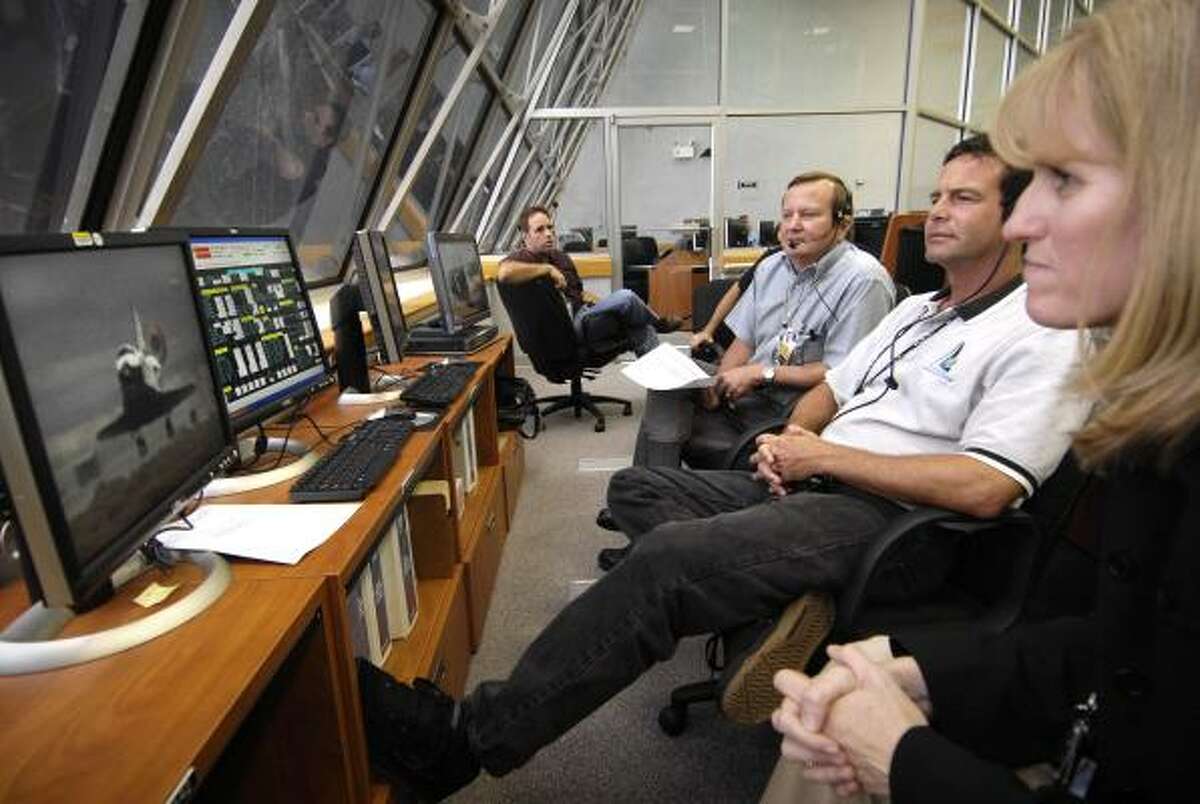 Atlantis flow manager Angie Brewer, assistant launch director Doug Lyons and shuttle launch director Michael Leinbach, from right, watch the landing at Cape Canaveral, Fla.