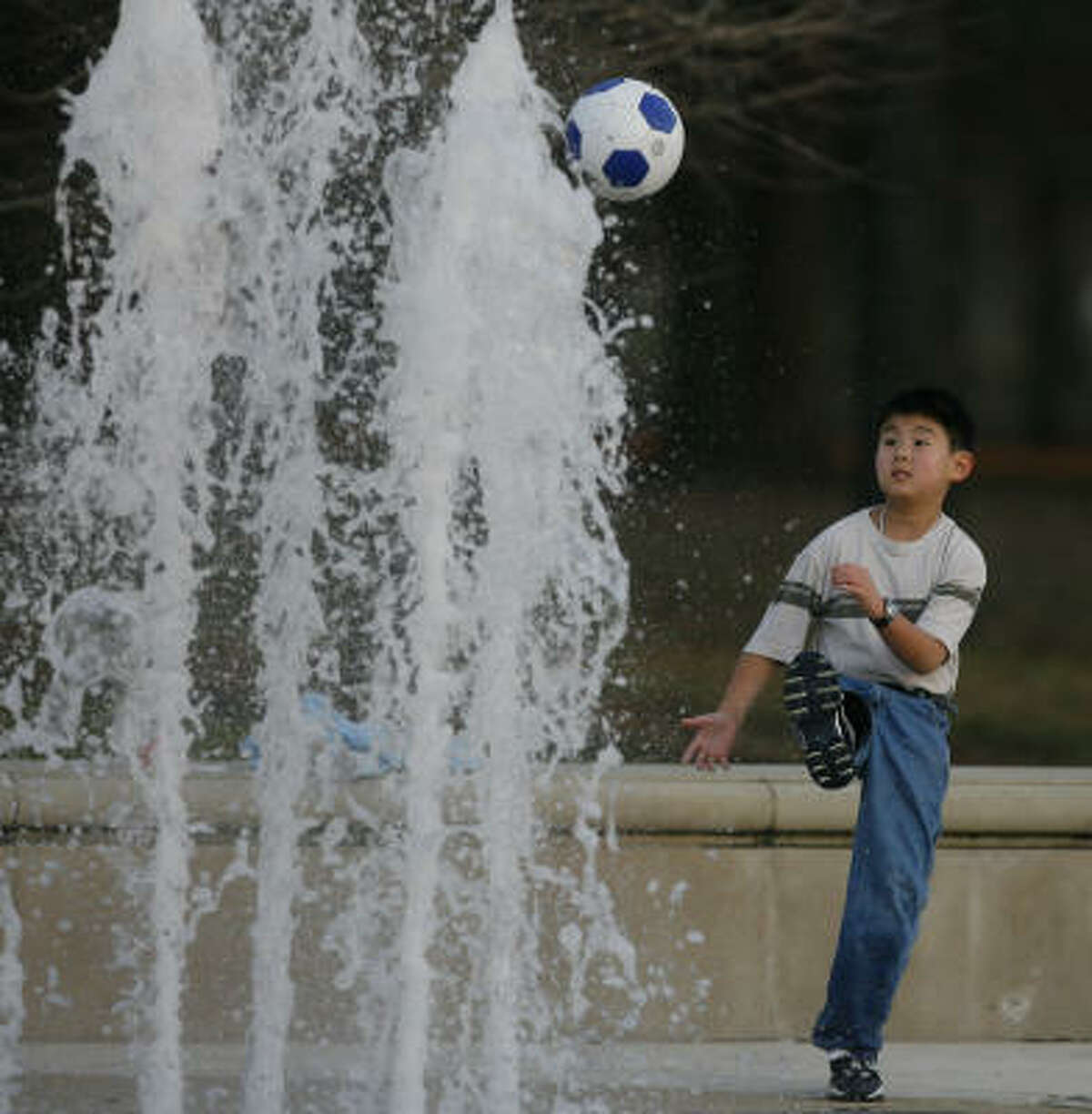 Paul Tan, age 10, tries to kick a soccer ball over a fountain in Hermann Park while enjoying some pleasant weather earlier this month.