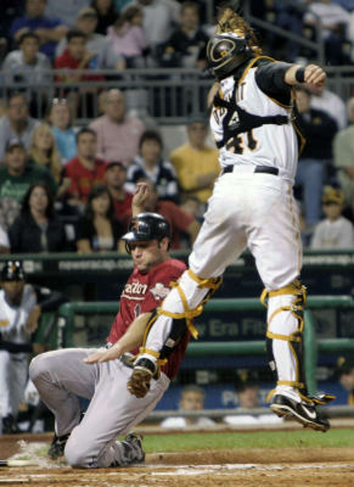 Pittsburgh Pirates catcher Ryan Doumit, top, leaps for a bad throw from left fielder Nyjer Morgan as Astros first baseman Lance Berkman, bottom, scores in the fourth inning on Friday at PNC Park in Pittsburgh.