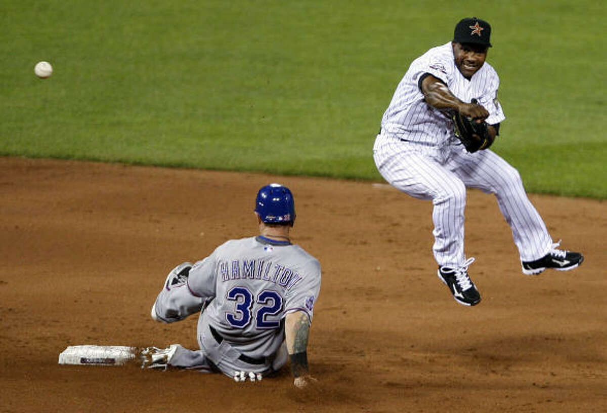 The Astros' Miguel Tejada, right, forces out Josh Hamilton and turns a double play by throwing to first base.