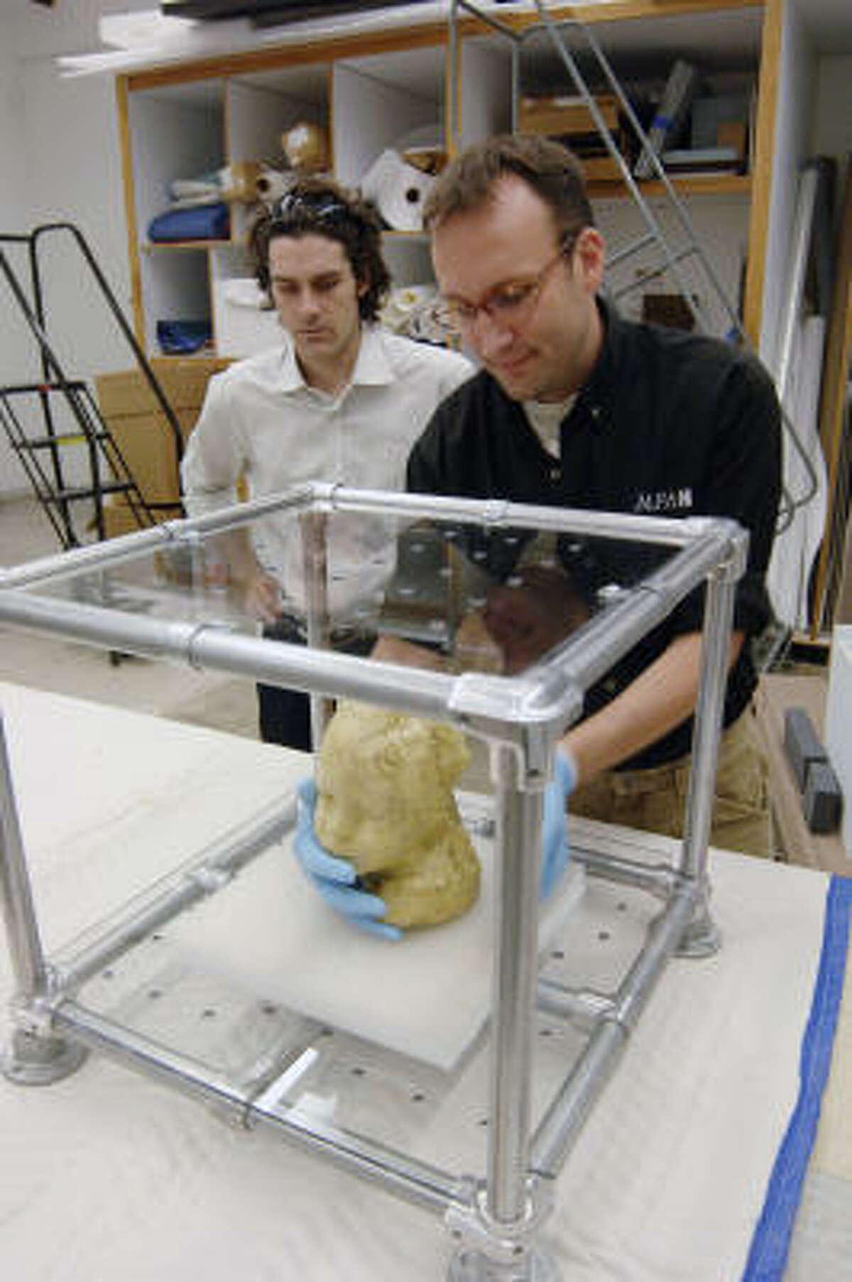 Matthew Wettergreen, left, a Rice University lecturer, supervises as Museum of Fine Arts, Houston, preparator Michael Crowder installs a wax-and-plaster sculpture into a working storage-system prototype developed by Wettergreen's students. Because the structure is made of Plexiglas and a steel armature, it allows the artwork to remain visible while in storage.