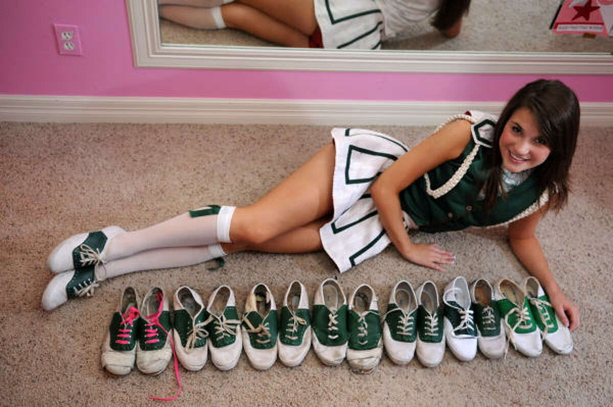 Sarah Amelunke, 17, The Woodlands Highstepper First Lieutenant, is surounded by a collection of her old Highstepper shoes, including a pair with pink strings which were passed from former Major Lauren Gronberg to Major Alex Eppler and then to Sarah, a pair of original green shoes which have been passed down for many years and now belong to Major Kylie Phillips, and a single shoe passed down to Sarah from 2006 graduate Katie Sewell, who lost the other shoe.