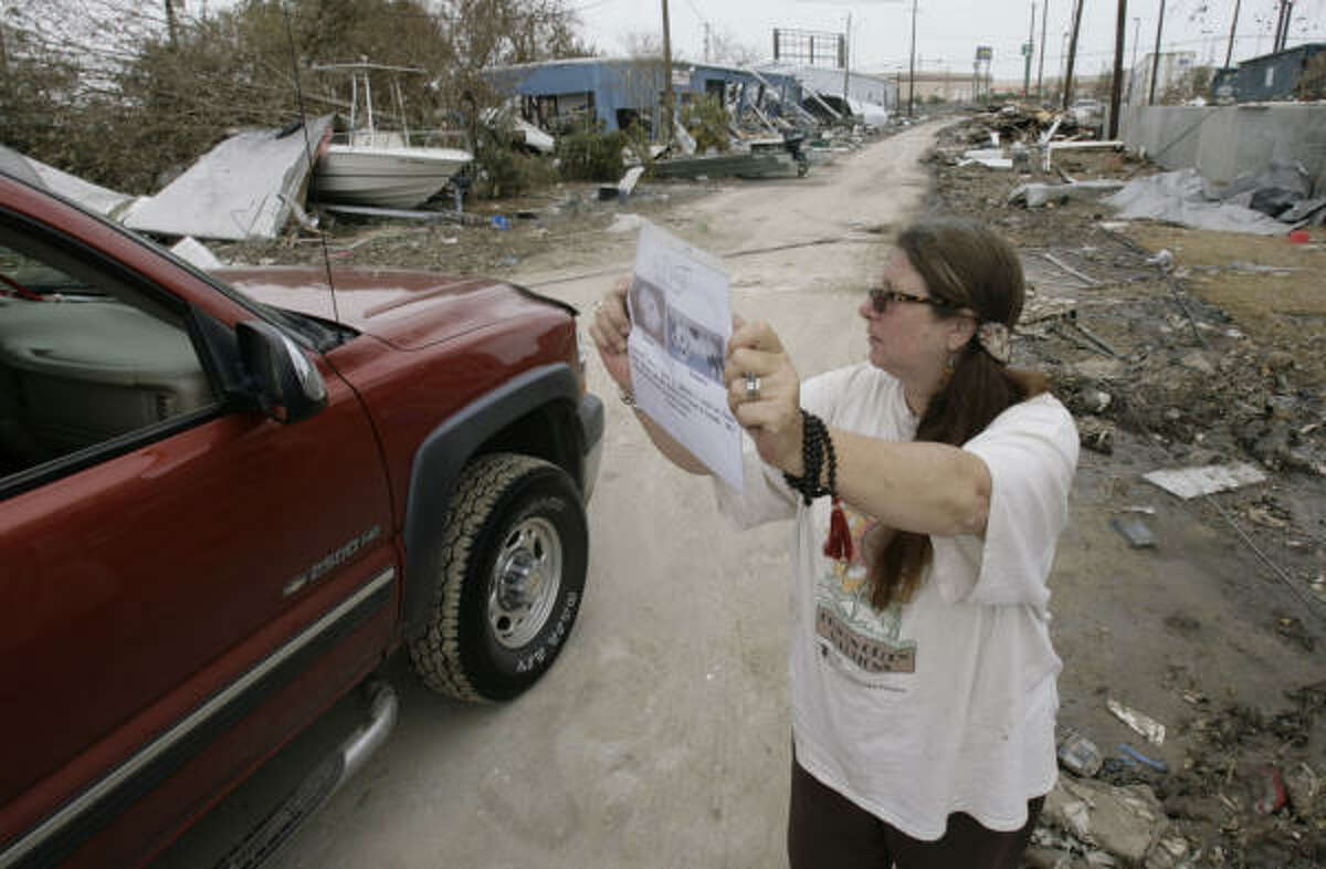 Kat Joel-Reich, 56, right, holds up a sign with the photos and information of Biscuits and Toonees, two cats owned by her friend Jennie Gounah that went missing after Gounah's house collapsed during Hurricane Ike, as she asks people in a car if she's seen the cats roaming anywhere in Galveston Island.