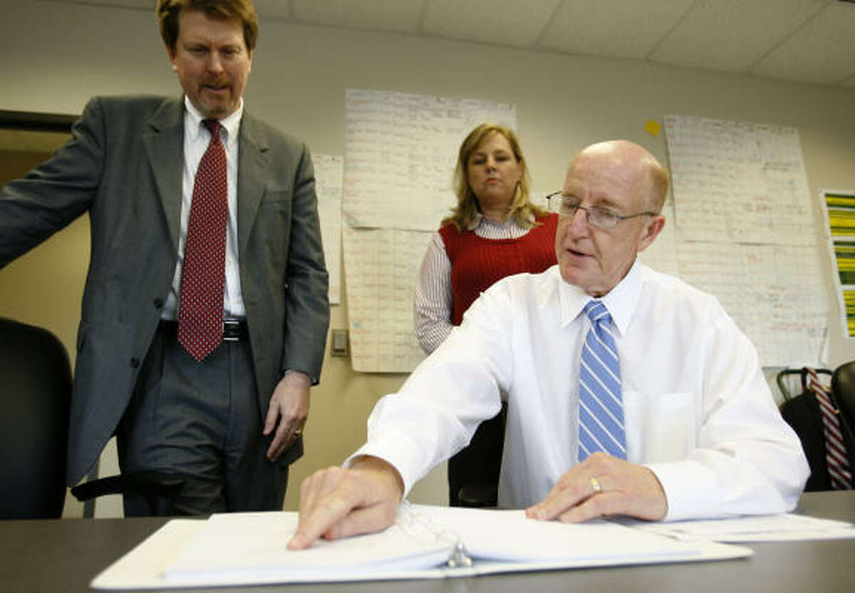 Bob Wicoff, seated, looks over some paperwork with Thomas Martin and Kelly Smith. The three have been appointed to review Harris County cases in which DNA evidence may be key.