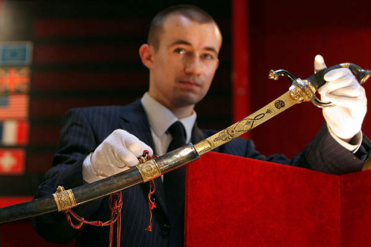 An auction house employee displays a gold-encrusted sword Napoleon wore into battle during its auction at the Fontainebleau auction house, southeast of Paris, Sunday. The buyer was not immediately identified.
