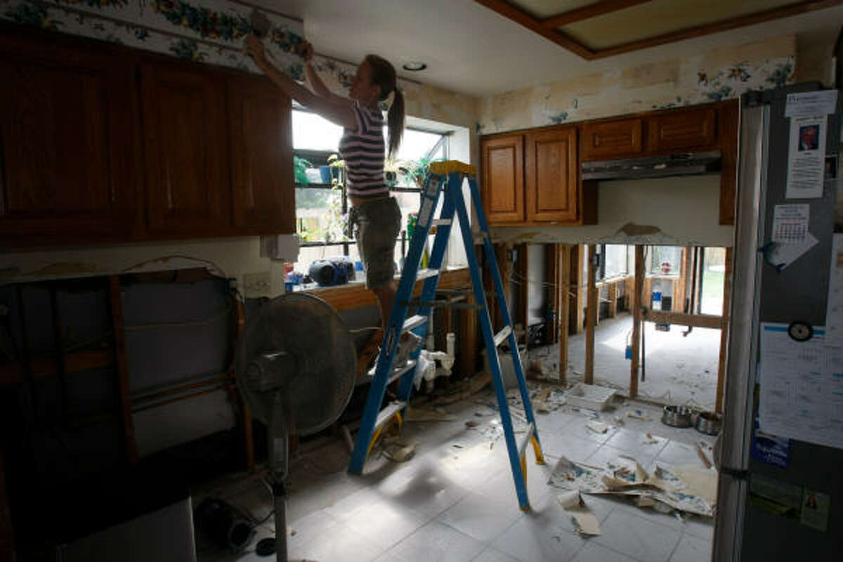 Kathleen Sheldon, of Earthquest Interiors by LJL, pulls off wallpaper in the kitchen of Dan Rayne’s house in Bear Creek, which was damaged by the heavy floods of April 27 and 28. Rayne, who fled with his two daughters to an upstairs loft as the waters rose, said, “I pretty much lost my whole downstairs.”