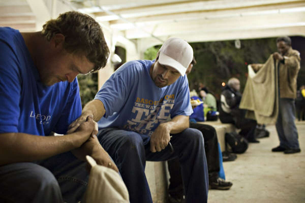 Bobby "Tre9" Herring, center, prays with John Bradley who had been on the streets for 41/2 months after his roommate lost his job and created financial stress during Feed a Friend anniversary event, Nov. 12, 2010, in Houston, under the Main Street bridge near downtown.