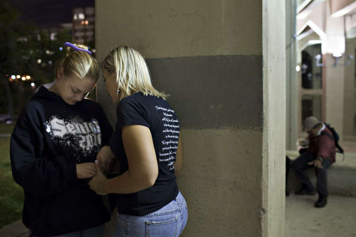 Bethany Jenkins, left, who has been homeless for 3 years, prays with Amanda Herring, wife of Bobby "Tre9" Herring, at the Feed a Friend anniversary event, Nov. 12, 2010, in Houston, under the Main Street bridge near downtown.