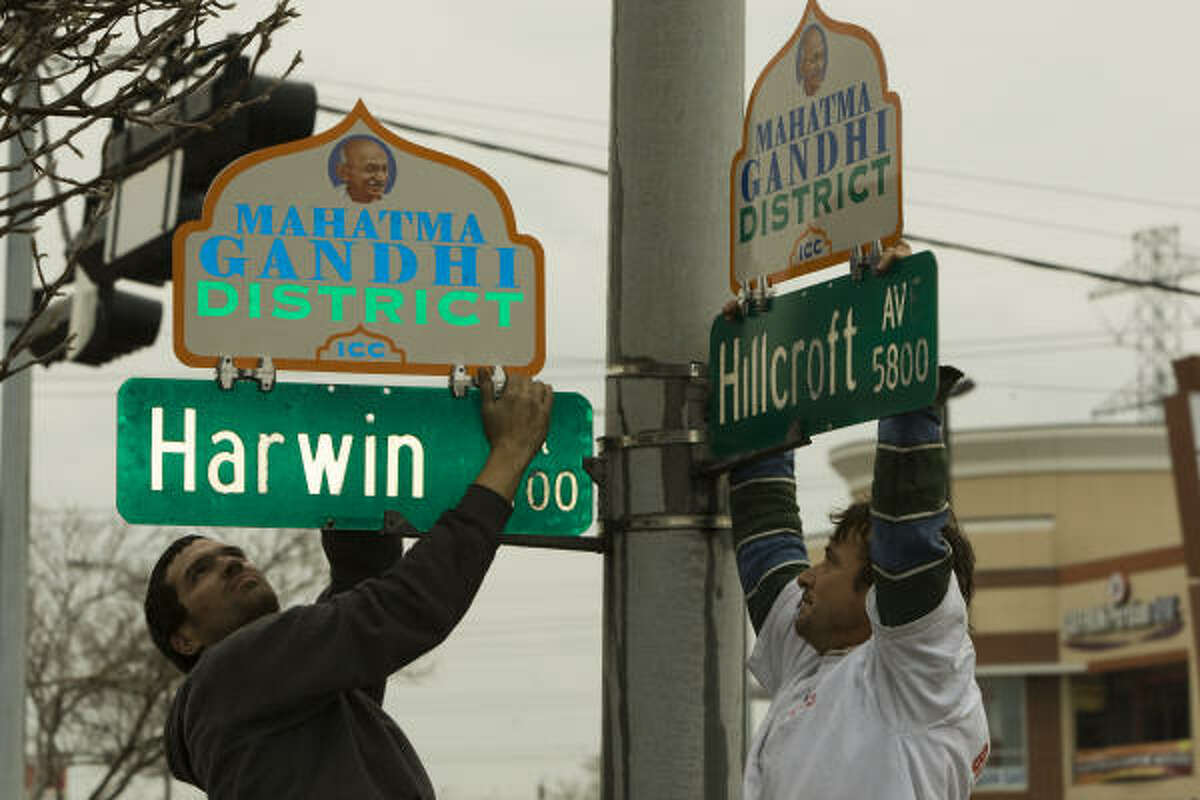Zane Frazar, left, and Ron Mitchell hang two of 31 new signs that demarcate the Mahatma Gandhi District on Friday. A ceremony is scheduled to inaugurate the new district in the Hillcroft-area neighborhood.