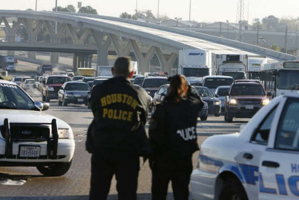 Houston police officers divert traffic from ice-covered lanes on Interstate 10 westbound at the Taylor street exit early Saturday morning.