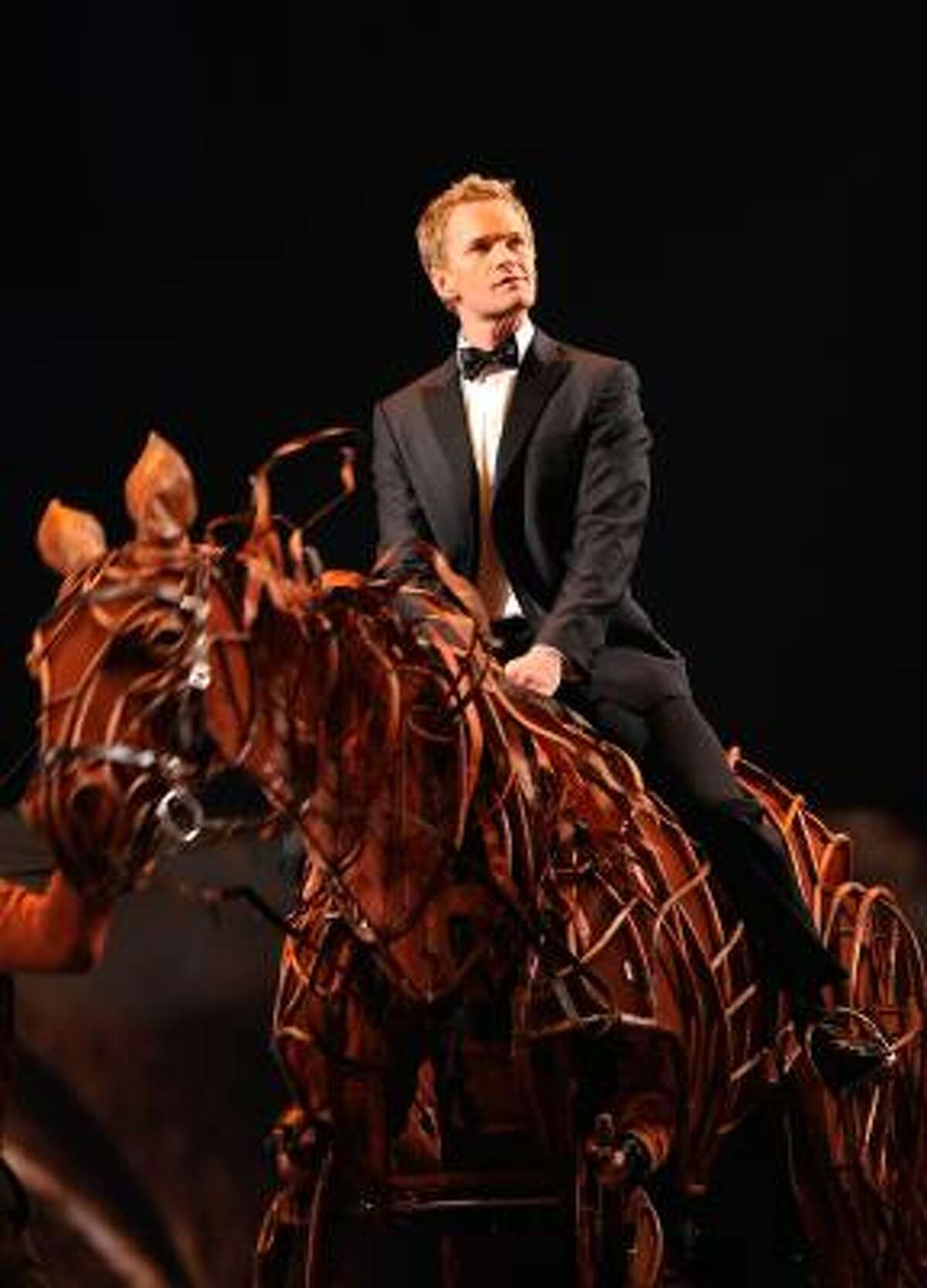 A puppet from War Horse takes host Neil Patrick Harris to the stage.