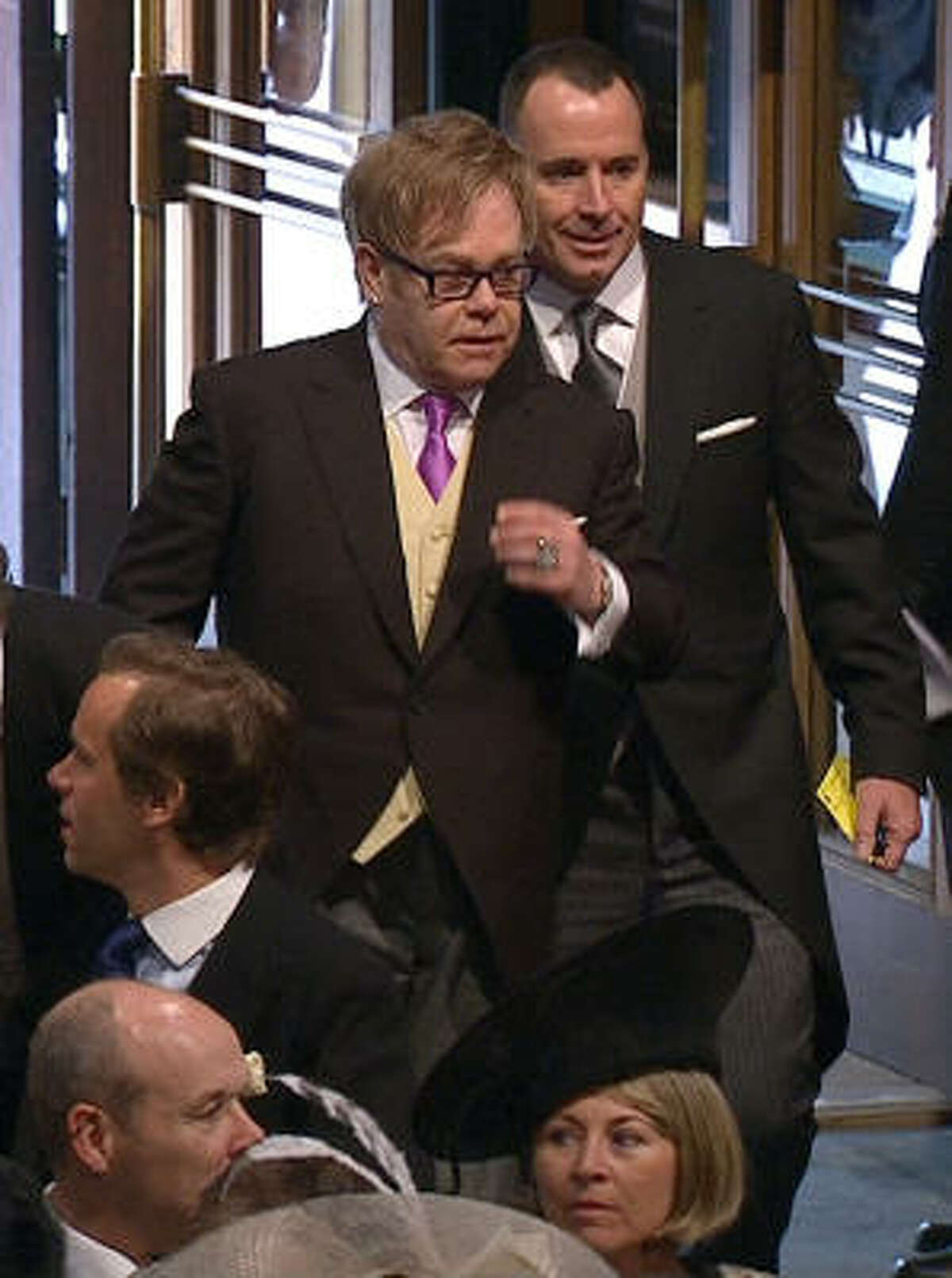 In this image taken from video, British singer Elton John, left, and his partner David Furnish arrive at Westminster Abbey.