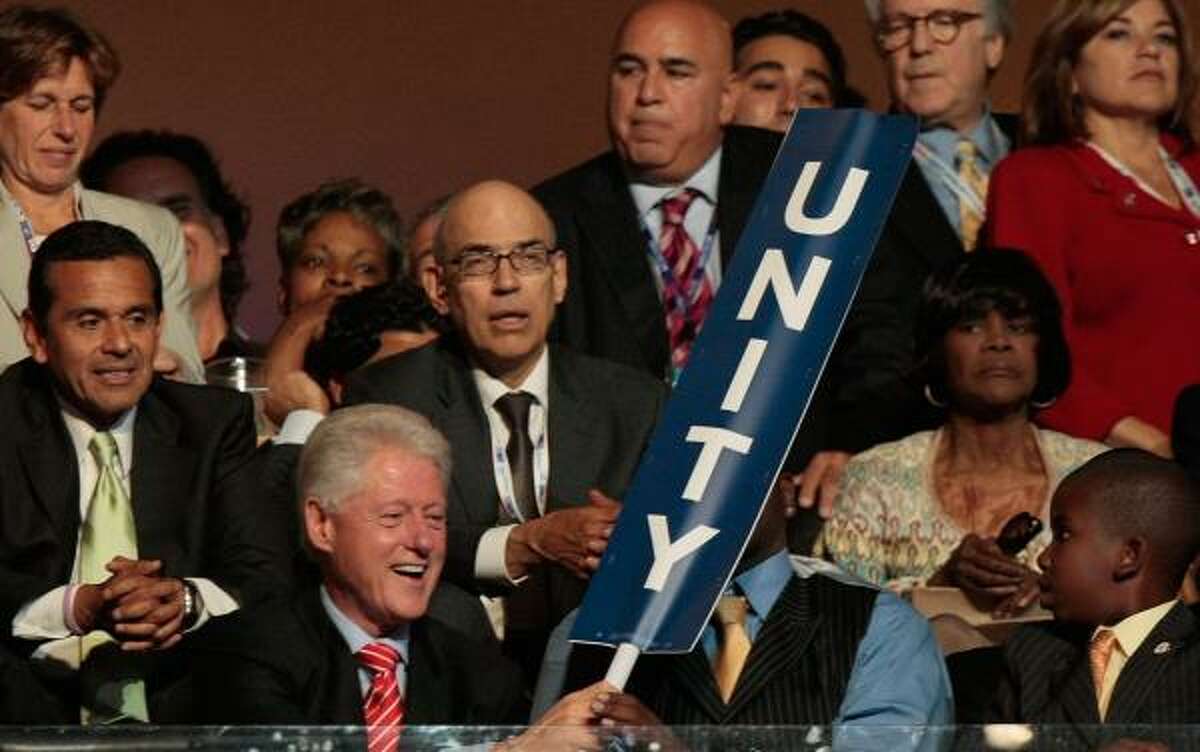 Former President Bill Clinton holds a "Unity" sign as he sits in the audience at the Democratic convention Tuesday night.