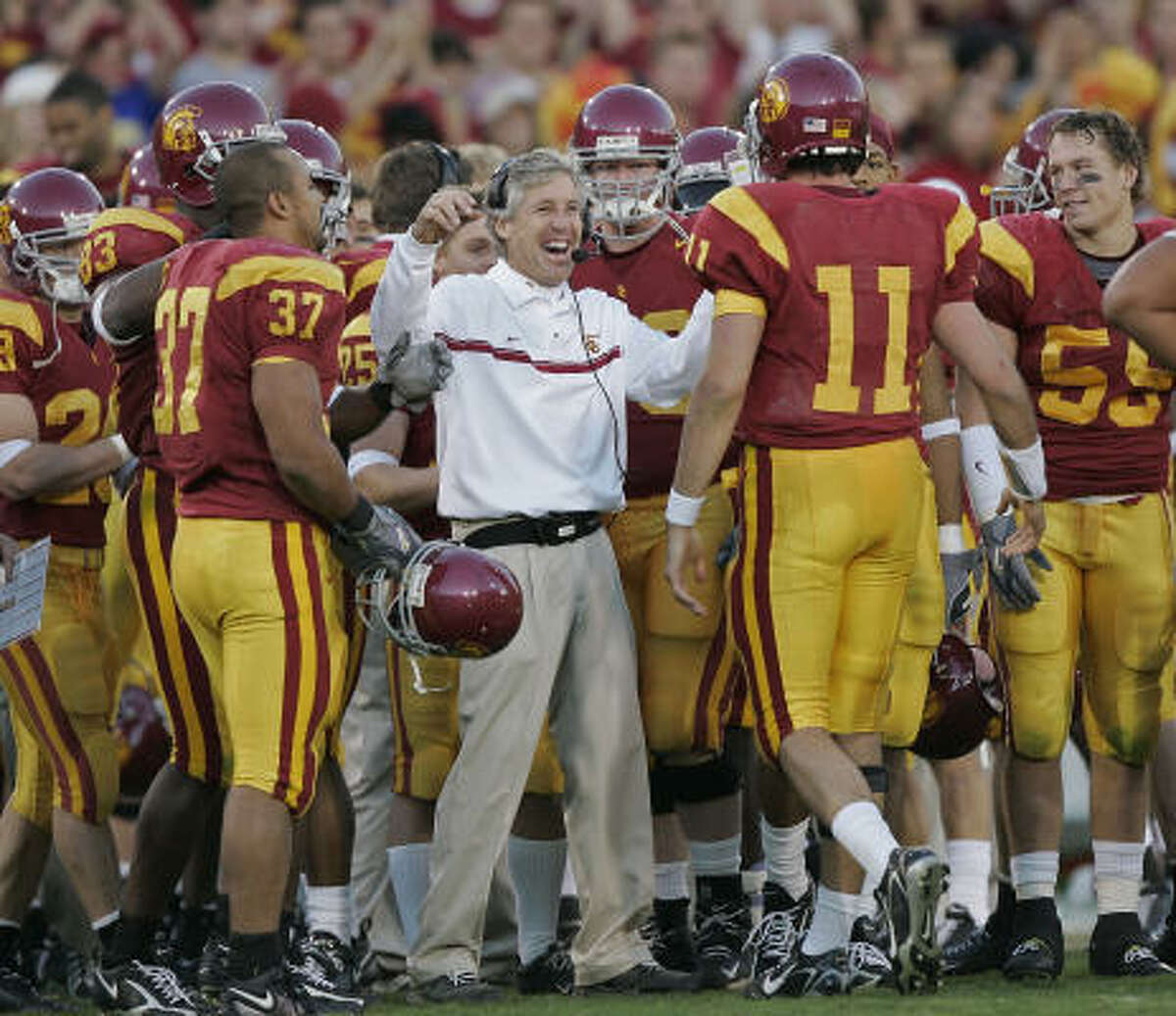 Pete Carroll, center, has been the face of USC football since 2001, during which time he has coached three Heisman Trophy winners, including quarterback Matt Leinart (11), won a BCS crown plus a writers' title, compiled a 34-game win streak and won games over 37 ranked opponents.