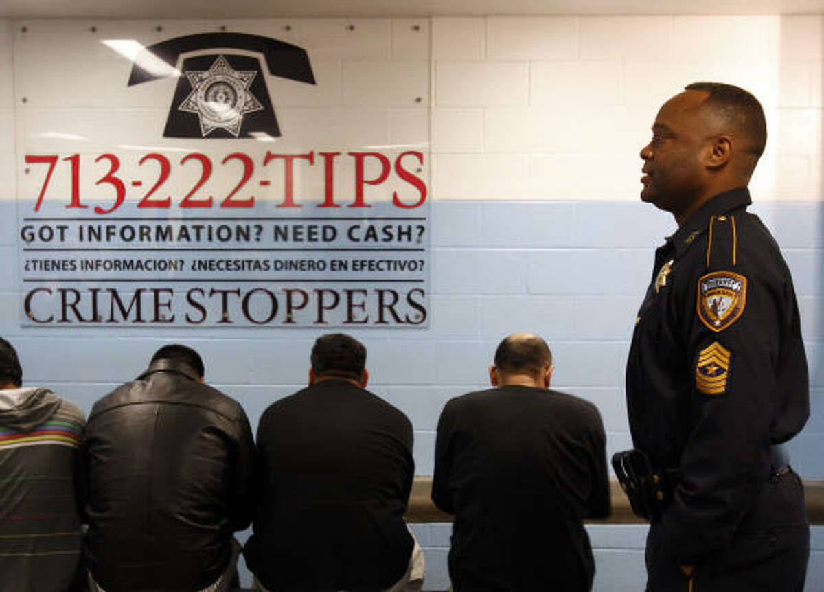 Sgt. Ronnie Holmes works at the Inmate Processing Center, where Crime Stoppers information graces the walls. The tips program initiated by Sheriff Adrian Garcia will have six monitors that flash Crime Stoppers data continuously in English and Spanish.