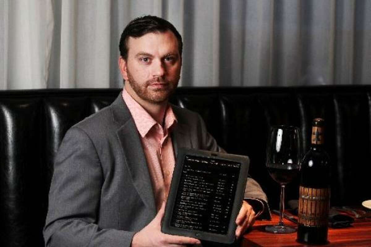 III Forks restaurant wine sommelier Brian Kelley holds an iPad with restaurant electronic wine menu.