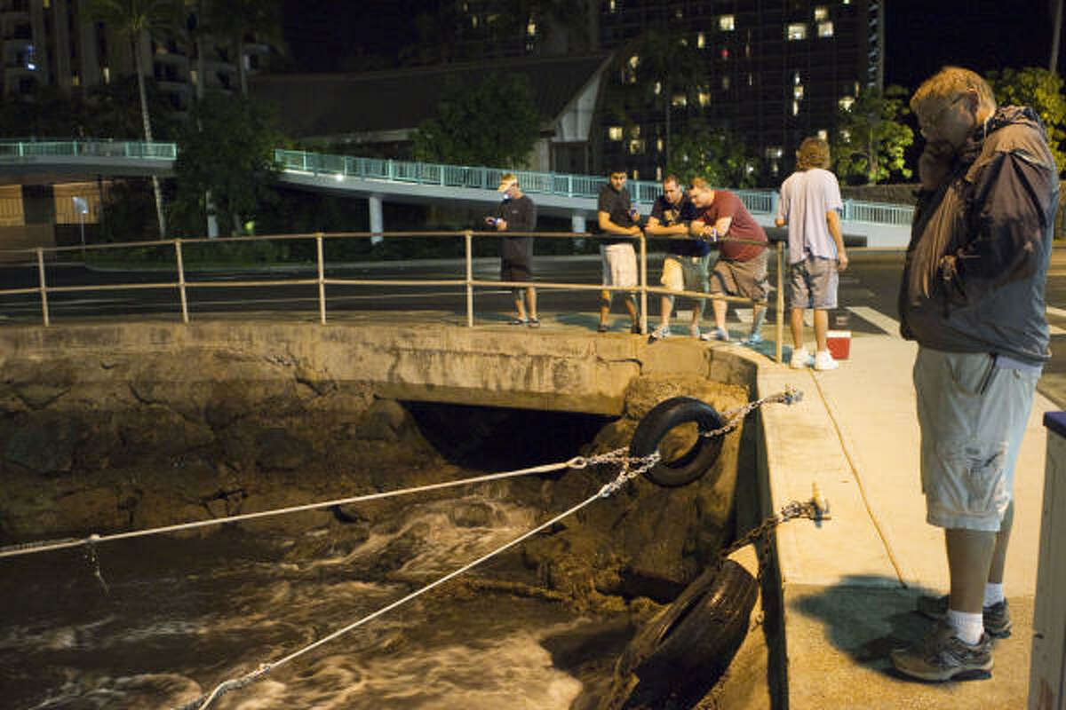 People watch the water recede from Hobron Harbor in Honolulu. Tsunami waves swamped Hawaii beaches before dawn but didn't cause any major damage after devastating Japan. March 11, 2011.