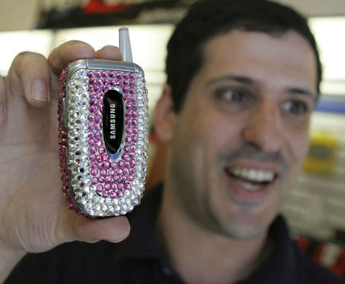 Adam Anolik shows a decorated phone in his wireless phone store in Philadelphia. Cell phone accessories have become a $1 billion business.