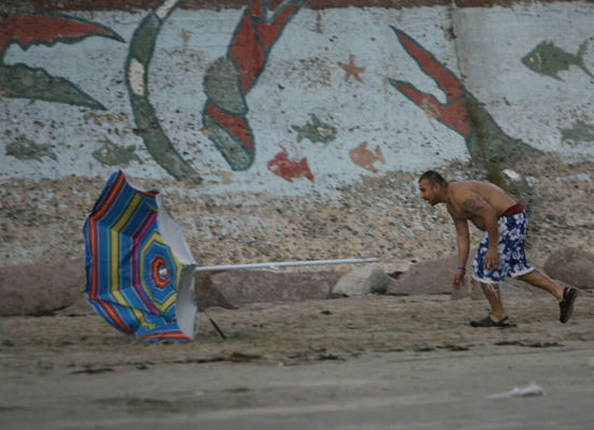 Johnny Herrera, of Houston, chases his umbrella as the wind picks up slightly near the seawall in Galveston Sunday. Much of southeast Texas was under a thunderstorm watch Sunday night.