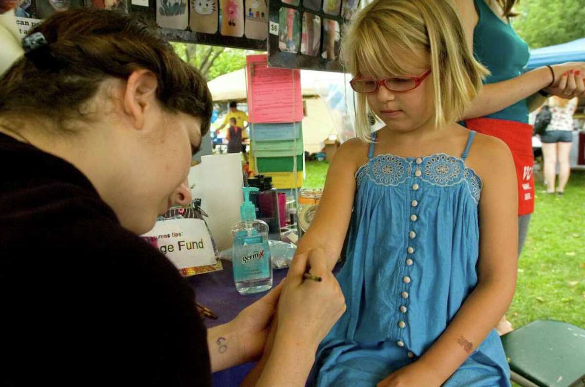New Milford resident Skyler Gustas, 9, gets her arm painted by Lauren Jelenffy, of Village Center for the Arts in New Milford, during the 44th Annual New Milford Village Fair Days on Friday, July 29, 2011.