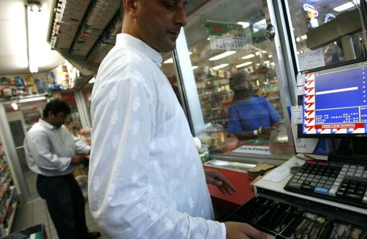 Store clerk Ali Khan, center, works the register while Farooq Haroon, left, helps customers at the Valero store at the intersection of West Gulf Bank and Veterans Memorial in Houston.