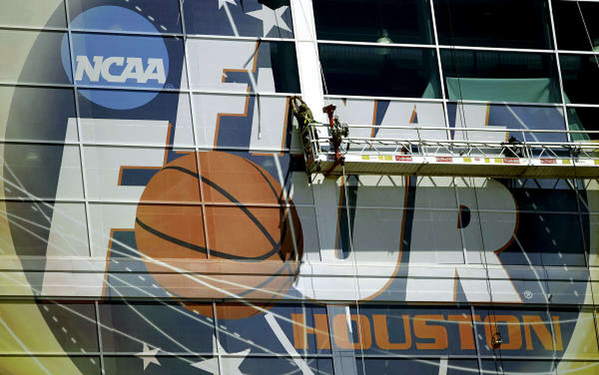 Workers peel off the Final Four sign off of Reliant Stadium.