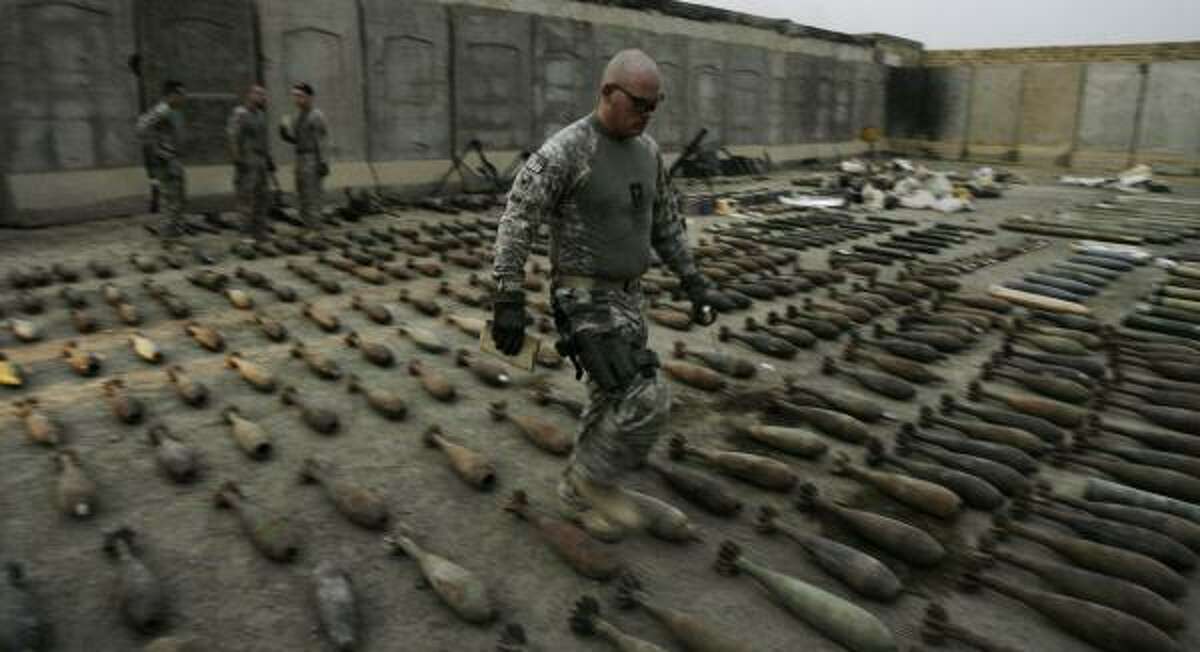 A U.S. soldier from the Explosive Ordinance Disposal team walks through recently seized munitions Tuesday at a joint U.S.-Iraqi army base in Sadr City, Baghdad.