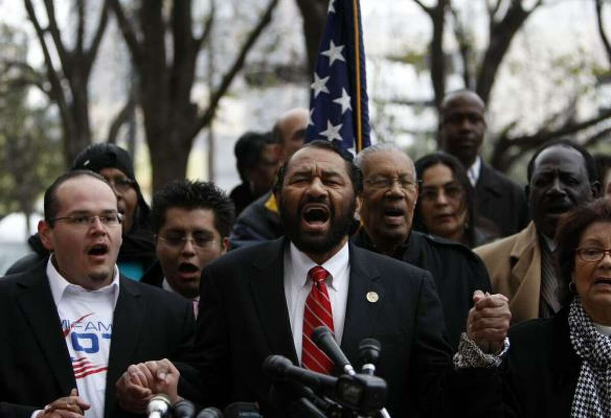 Rep. Al Green, D-Texas, center, sings "God Bless America," as a group of people gathered out front of the Mickey Leland Federal Building in Houston during a nationwide moment of silence Monday called for by President Obama in response to the shooting that killed six people and critically injured Rep. Gabrielle Giffords, D-Ariz.
