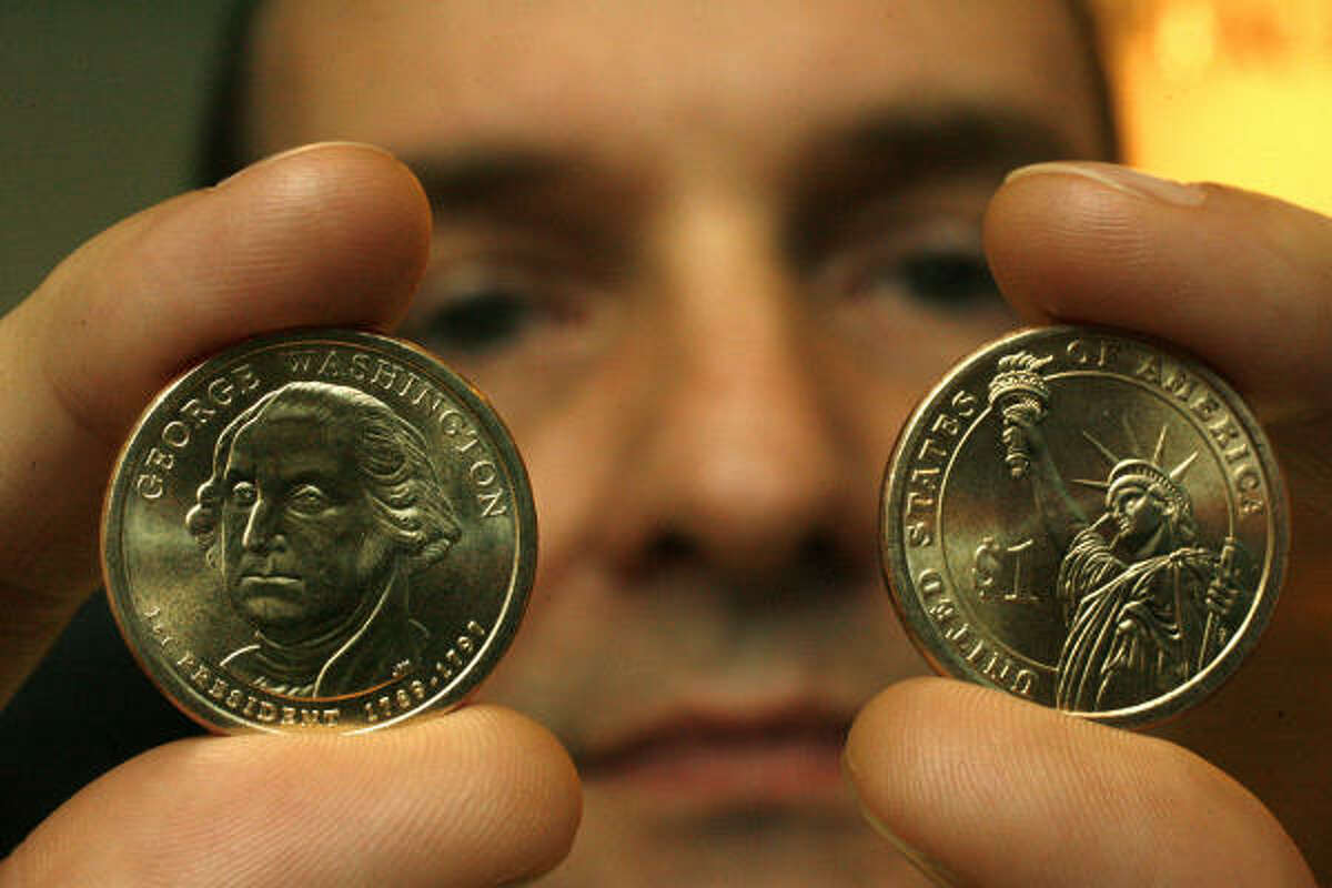 Kenneth Rollo of the Houston branch of the Federal Reserve Bank holds the first in a series of $1 coins.