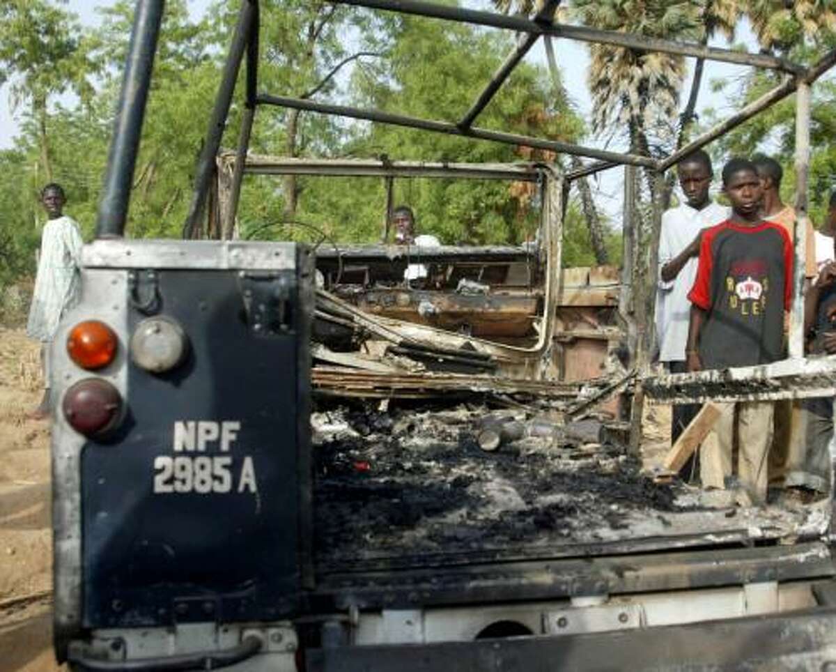 A police vehicle torched by gunmen Tuesday sits in Kano, Nigeria, which is under a nighttime curfew after unrest in recent days.