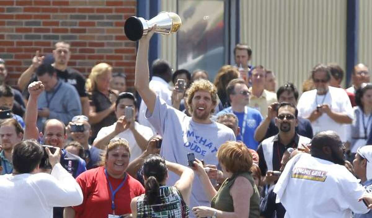 Mavericks forward Dirk Nowitzki hoists his Finals MVP trophy in a crowd after the Mavericks returned to Dallas Love Field.