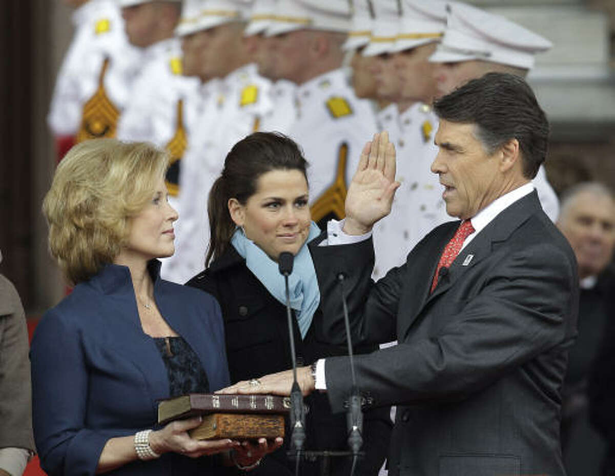 Gov. Rick Perry takes the oath of office as his wife, Anita, left, and daughter, Sydney, center, look on during his inauguration.