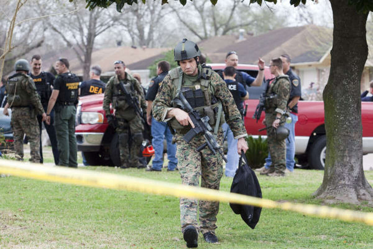 A Houston Police Department SWAT member leaves a raid where an officer was wounded Thursday. Two suspects were arrested, including one who was shot in a north Houston house. The officer is expected to survive; the suspect was listed as stable.