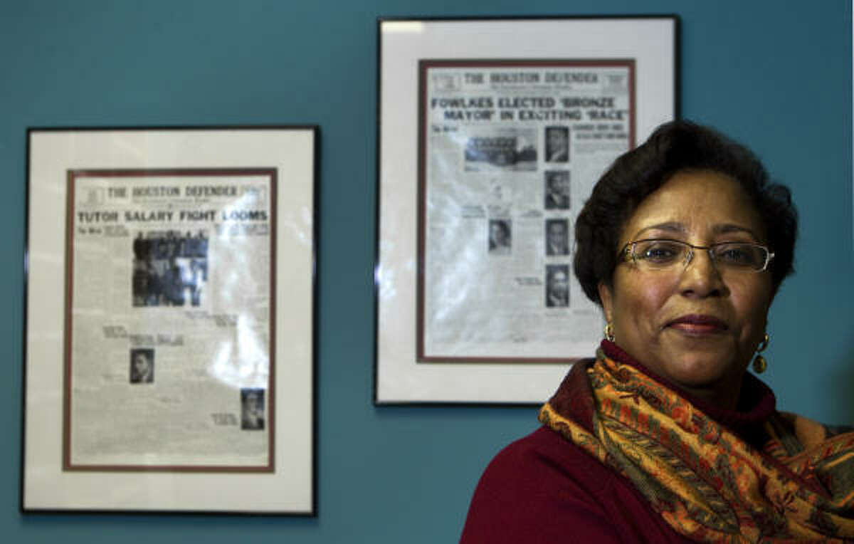 Sonceria "Sonny" Messiah-Jiles, publisher of The Defender, stands near framed vintage front pages from the publication at the offices of the newspaper. Next month, The Defender will mark 80 years of publication.
