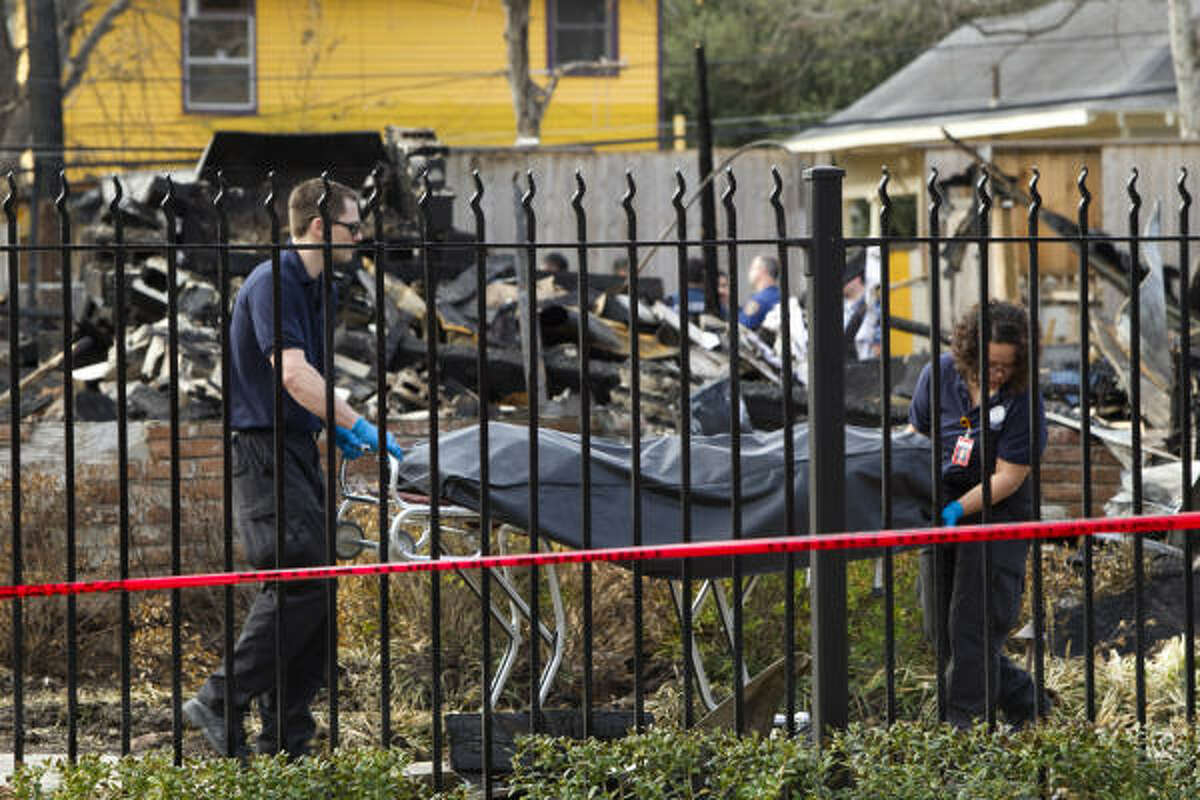 The last of the two bodies recovered in a deadly Heights house fire is wheeled from the scene Wednesday.
