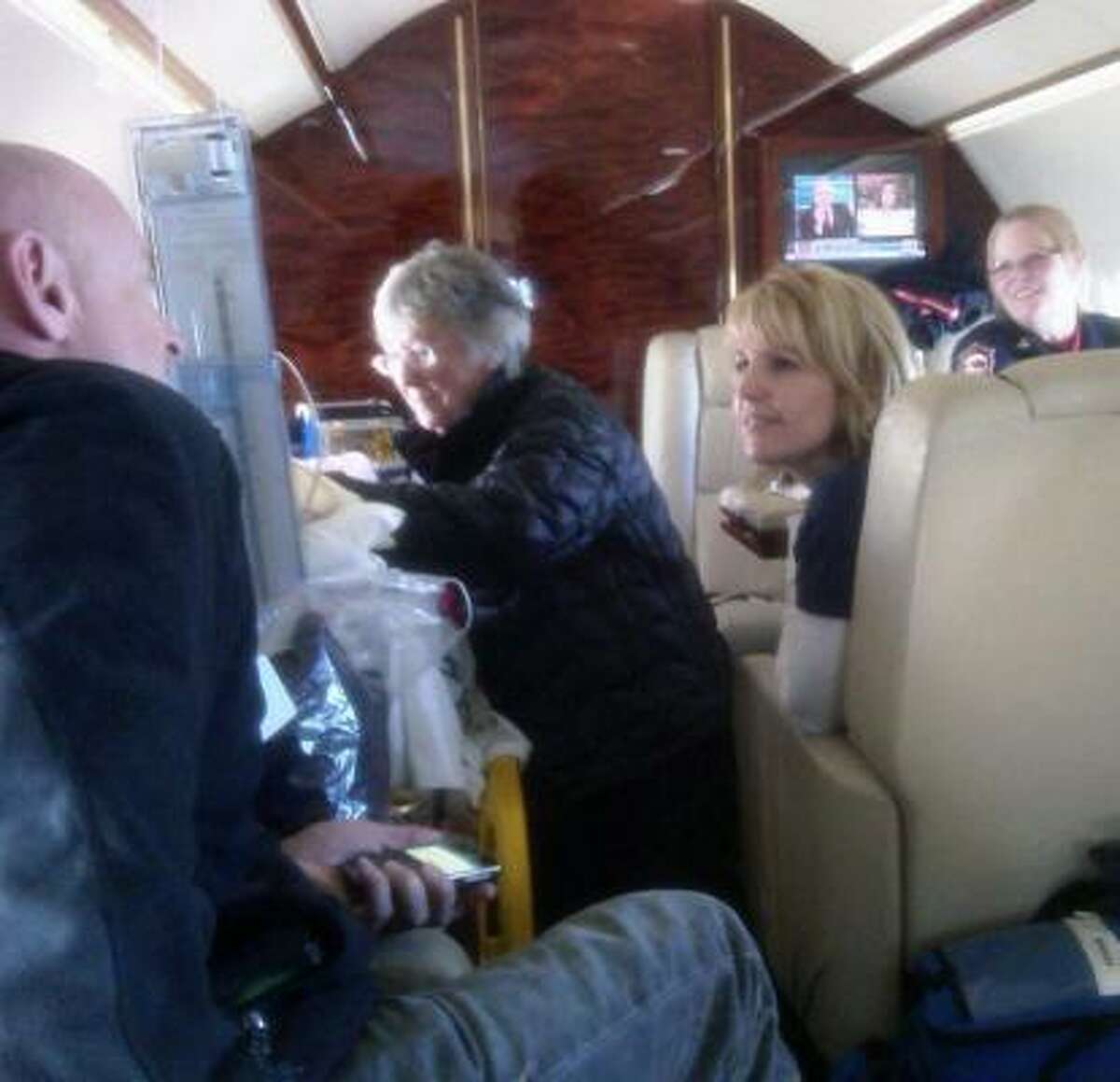 Gloria Giffords, mother of U.S. Rep. Gabrielle Giffords, attends to her Friday on the flight from Tucson to Houston. The congresswoman's husband, astronaut Mark Kelly, left, chats with one of Giffords' nurses, Tracy Culbert.