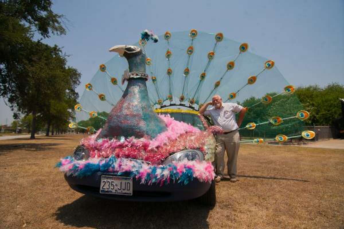 TAKING PRIDE: Mark Garrett of Jersey Village poses with "Percy the Peacock" outside the Art Car Museum. The peacock-mobile followed the mayor's car this year in the 24th annual Art Car Parade on Allen Parkway.