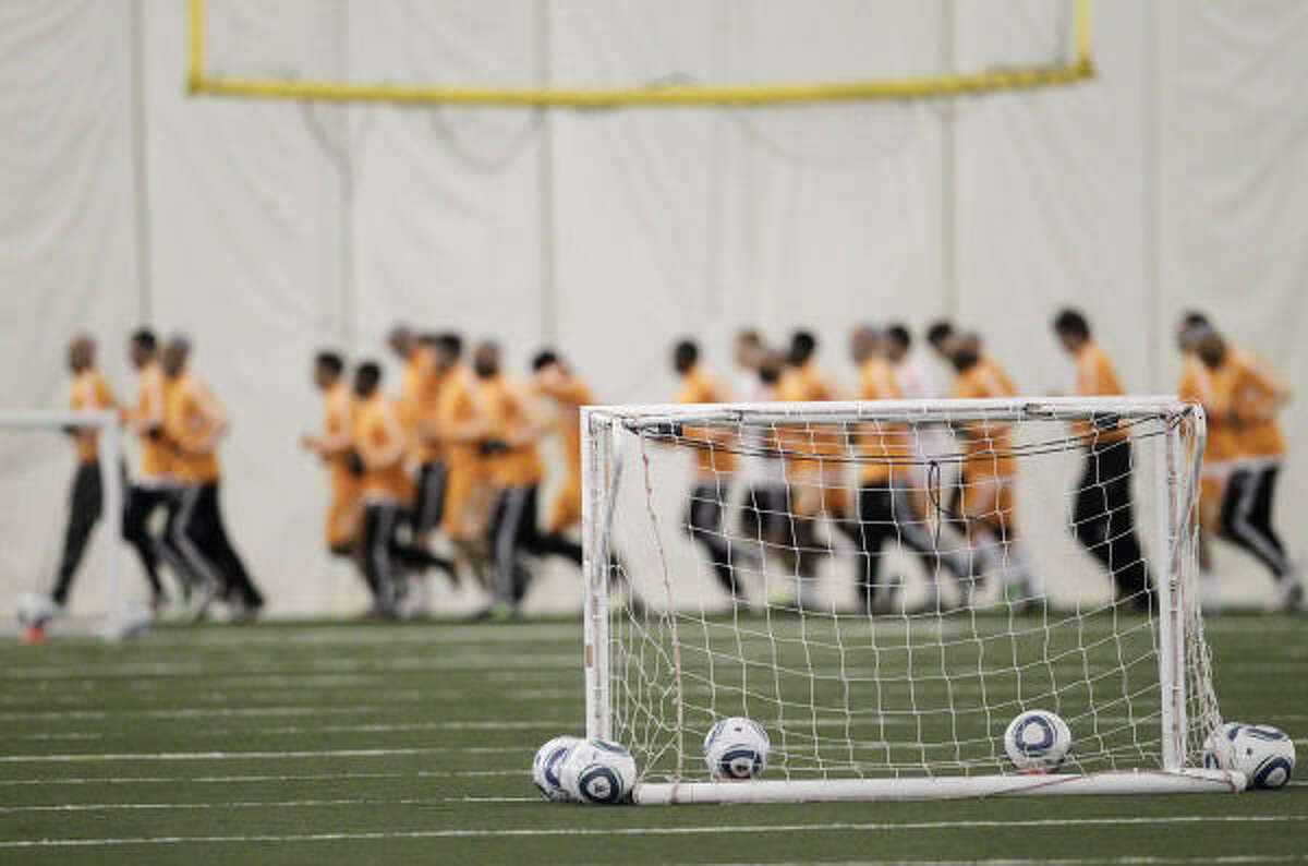 Dynamo players warm up by running before the start of practice Wednesday.