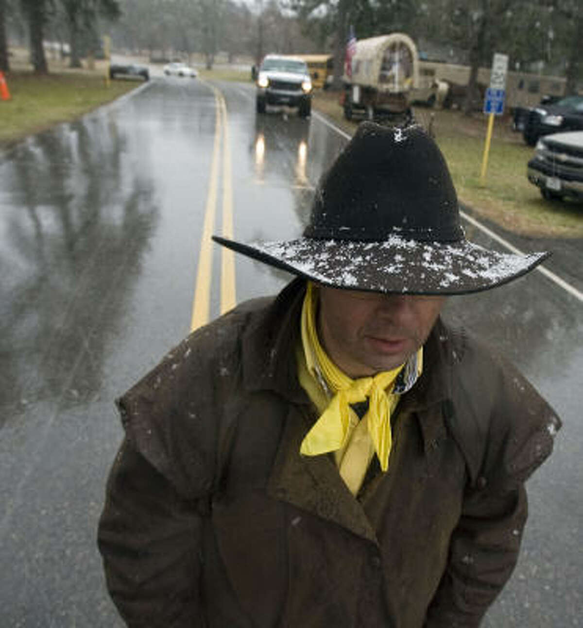Dion Vandenbosch with the Sam Houston Trail Ride walks through snow and sleet Tuesday after the group stopped for the night at Spring Creek Park in Tomball.
