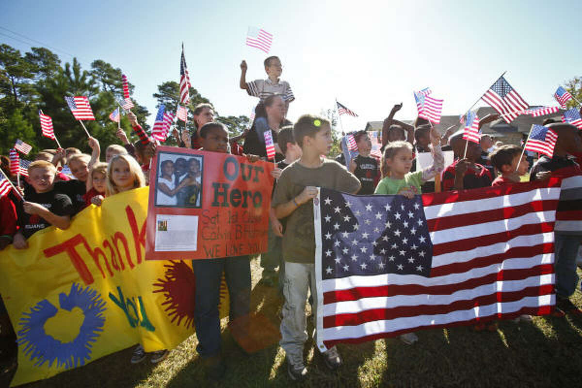 Elementary school students hold signs and flags Friday in honor of Sgt. 1st Class Calvin B. Harrison, who died in Afghanistan, as his funeral procession passes by in Coldspring.