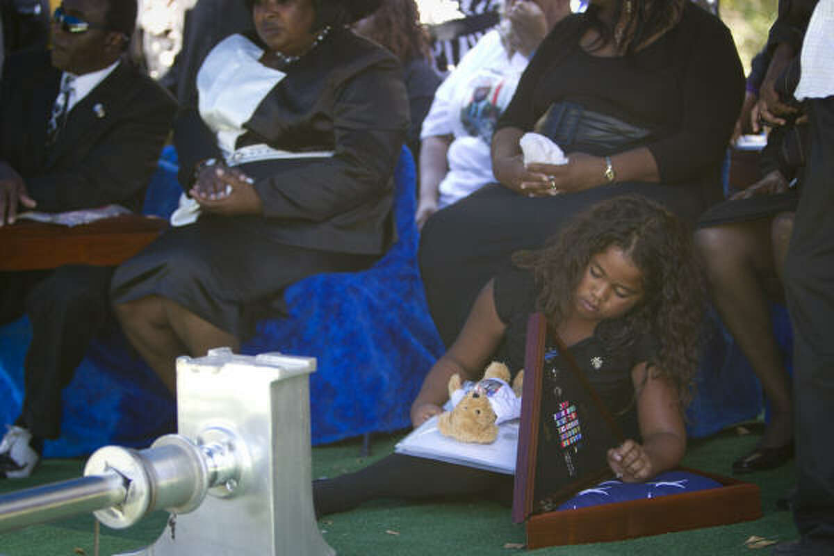Among the mourners at Friday's services for Sgt. 1st Class Calvin B. Harrison was his daughter Eleanna, who takes a moment with mementos of her father's life and military service. Harrison, 31, died Sept. 29 on his second tour of the Afghan war.