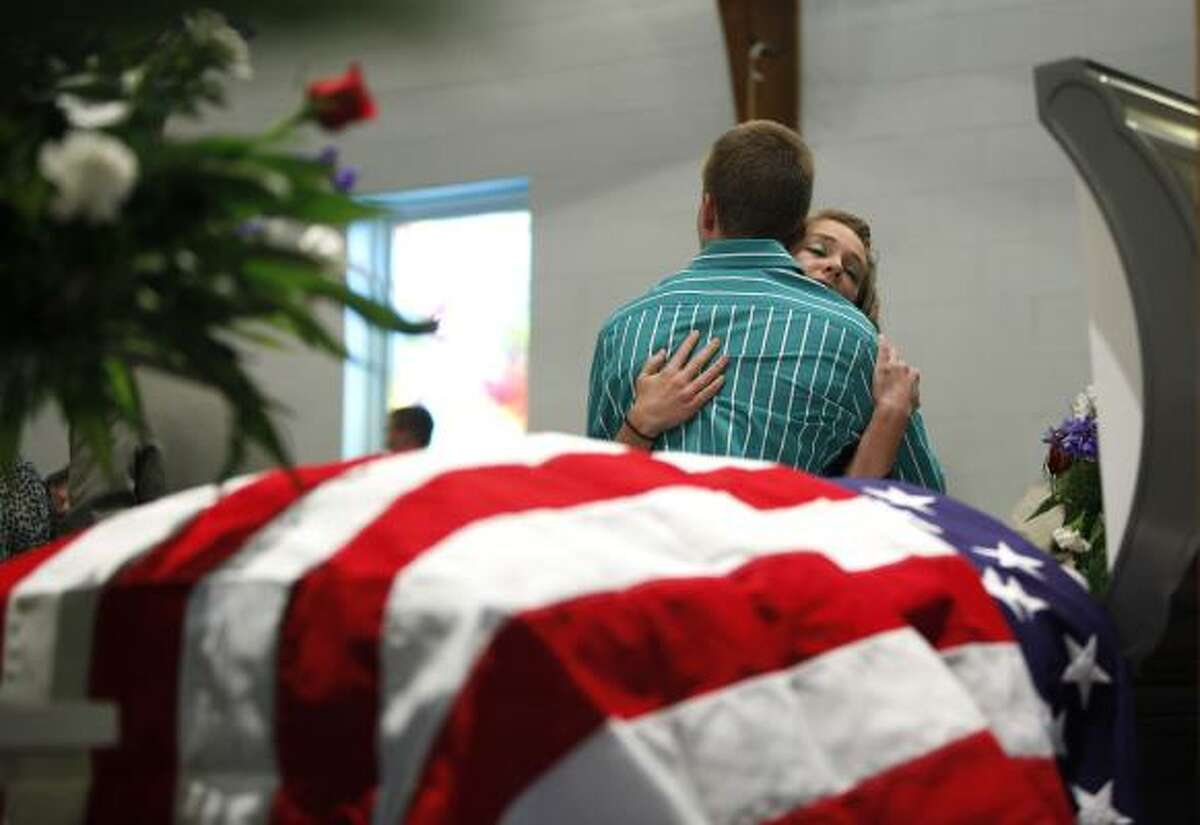 Travis McKinney is comforted by Cheyanne Graybeal next to the casket of McKinney's grandfather, mine victim Benny Ray Willingham, in Mullens, W.Va., on Friday.